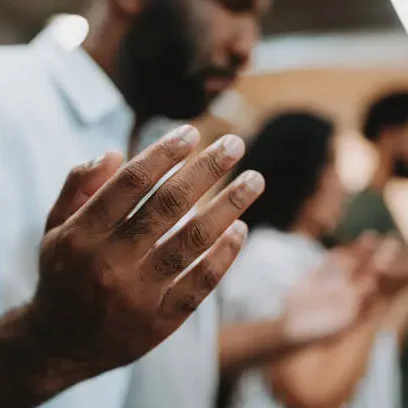 Man's hands in prayer, group praying.